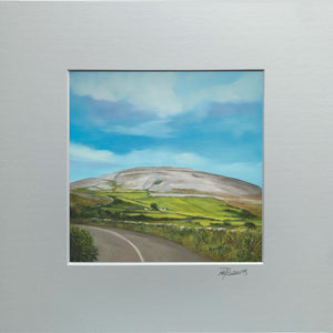 Framed artwork of a landscape with a road and green fields.