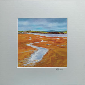 Framed artwork of a coastal landscape with a river and distant hills.